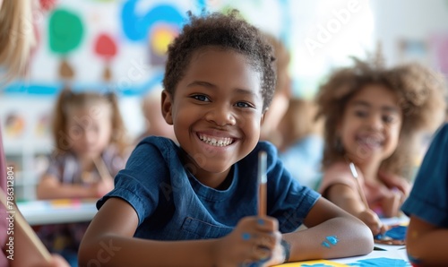Cheerful african american primary school girl smiling with toothy smile at camera in painting class classroom at school photo