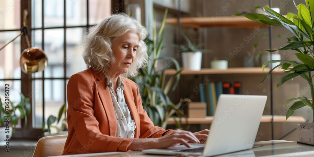 A woman in an orange jacket is typing on a laptop computer A woman in an orange jacket is typing on a laptop computer