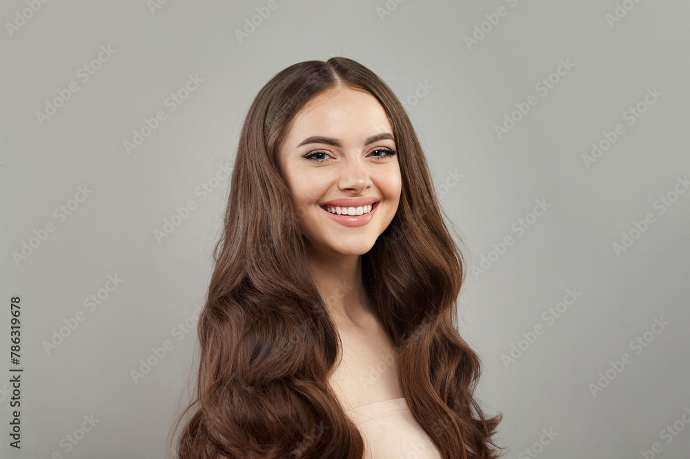 Emotional young happy woman model with natural make-up, clean healthy fresh skin and long hair posing on gray background. Curly, haircare, skincare and facial treatment concept Emotional young happy woman model with natural make-up, clean healthy fresh skin and long hair posing on gray background. Curly, haircare, skincare and facial treatment concept