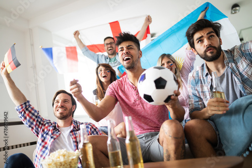 Cheerful and happy group of friends watching olympic games on tv. photo