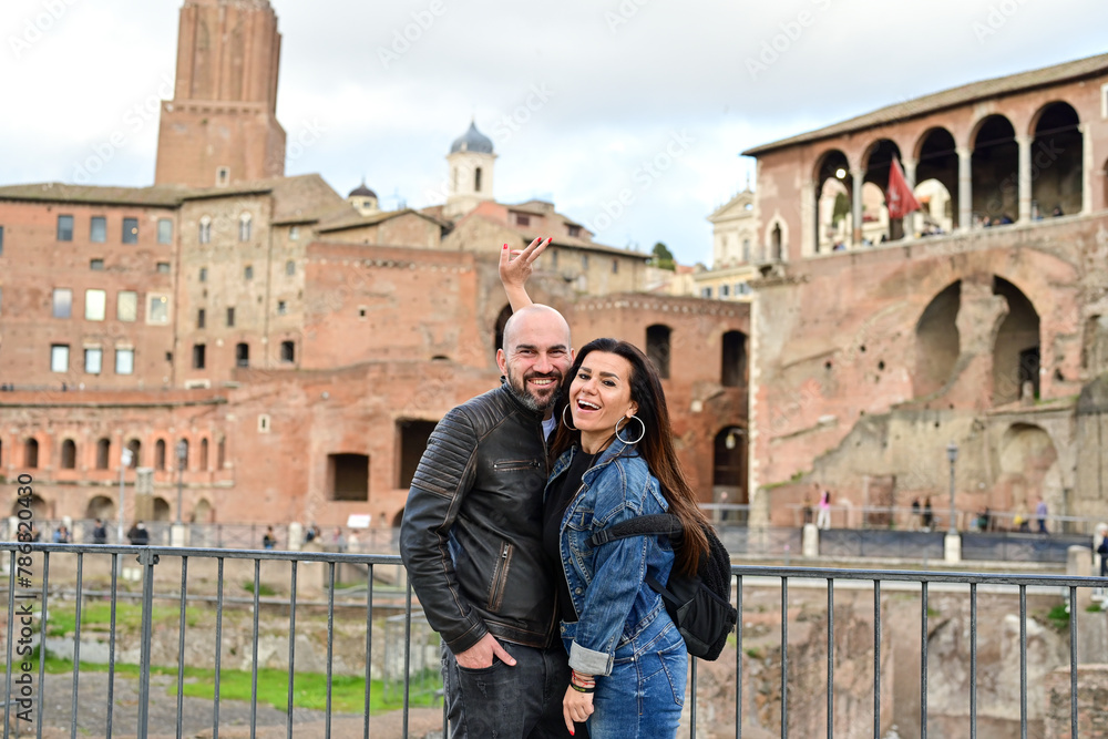 Happy  Beautiful Tourists  couple traveling at Rome, Italy,  near Ancient Trajan's Market, ruins in Via dei Fori Imperial Visiting Italy - man and woman enjoying weekend  weekend vacation 