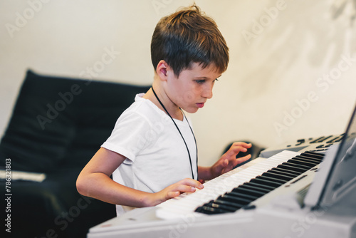 Young boy Portrait sitting at digital piano Playing keyboard focused kid activity indoors press on Key learning to play music room Hobby