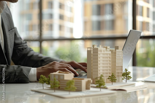 real estate business, housing development, property management. businessman working on laptop in office with building models on table. banner with copy space