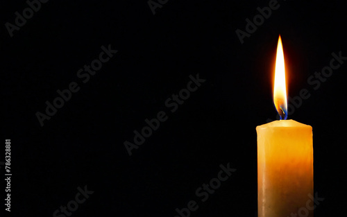 one burning candle on a black background with space for text close-up