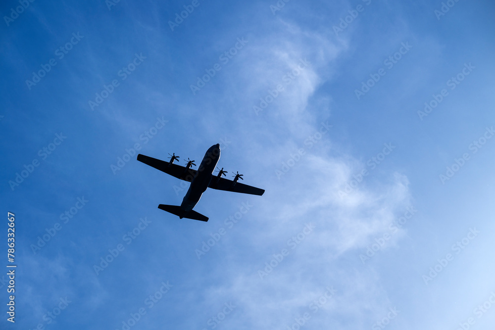 A military airplane silhouette on a blue sky A military airplane silhouette on a blue sky