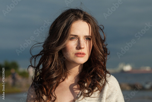 Glorious brunette woman with fresh skin, natural make-up and healthy wavy brown hair enjoying the sunny morning and sea air. Female model outdoor fashion portrait © millaf