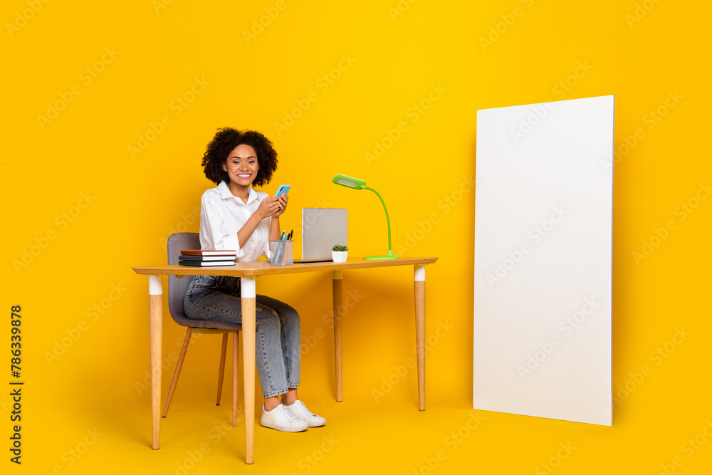 Full length body size view of beautiful trendy cheery girl using device working remotely isolated over bright yellow color background