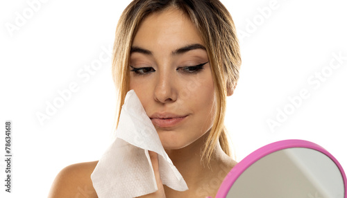 Obraz na plátne Attractive young woman cleaning her face with a wet tissue on a white background