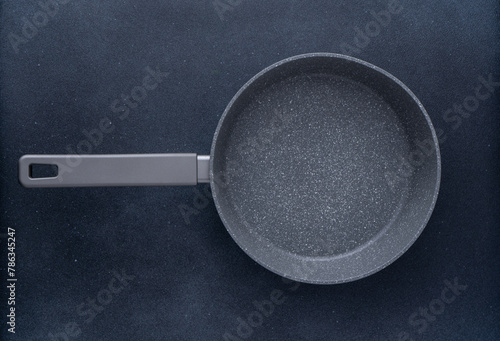 New granite frying pan on a gray background, top view. Empty fry pan with handle