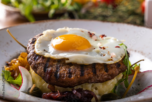 Grilled beef steak with fried egg and mushed potato.