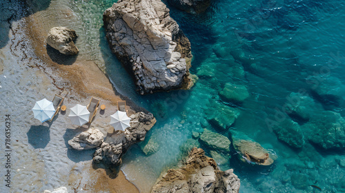 Drone view of rocky beach and sun chairs on shore 