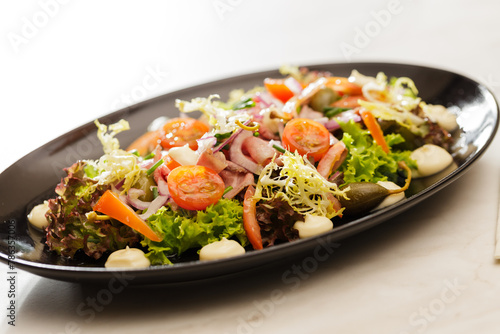 Fresh Vegetable green salad with sauce on a black plate