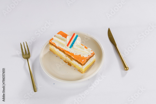 Dutch Oranje tompouce Cake with dutch flag on a white plate with gold cutlery for Kings Day photo