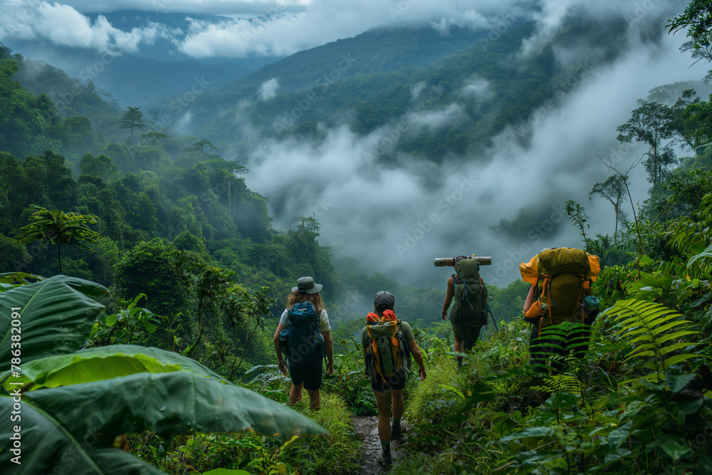Obraz premium Backpacker group hikes up a mountain in a rainforest area with views of forest, mountains and mist.
