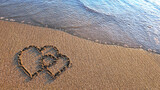 Two hearts drawn on brown sand of paradise beach