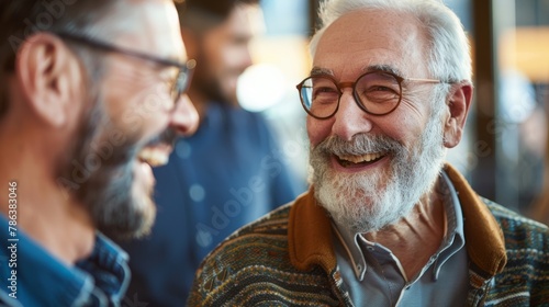 A closeup shot of two men with a beard and glasses, one smiling at the other with a joyful expression © Ilia Nesolenyi