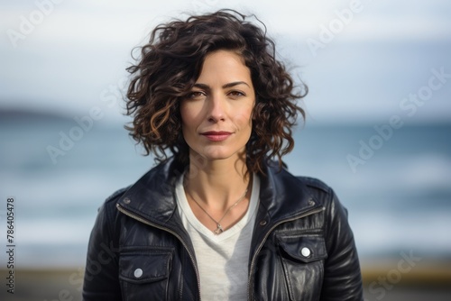 Portrait of a merry woman in her 40s wearing a trendy bomber jacket in tranquil ocean backdrop