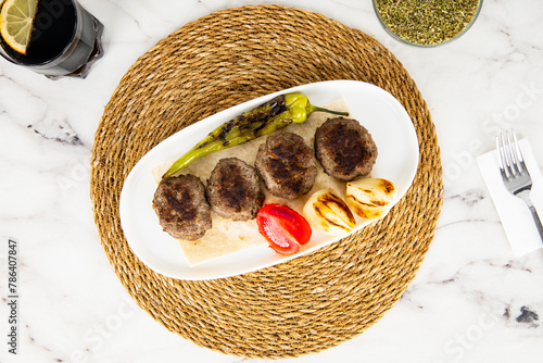 Meatballs with pepper, onions and tomato on white marble. Turkish Kofte