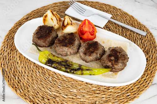 Meatballs with pepper, onions and tomato on white marble. Turkish kofte