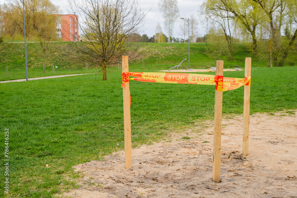 empty playground in the park. the site is fenced off with orange stop tape.