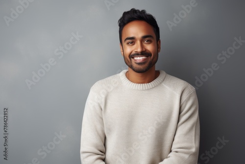 Portrait of a grinning indian man in his 20s wearing a cozy sweater in modern minimalist interior