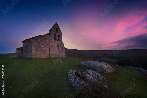 Sunset with dramatic sky in the Romanesque church of San Martín, in Quintanilla de la Berzosa, Aguilar de Campoo, Palencia, Castilla y León, with the tombs of the medieval necropolis in the foreground photo