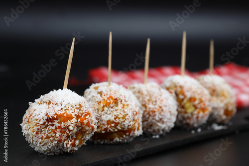 Beautiful sweets with coconut on a black plate on a black background close-up