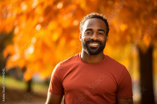 Portrait of a happy afro-american man in his 30s sporting a breathable mesh jersey while standing against background of autumn leaves