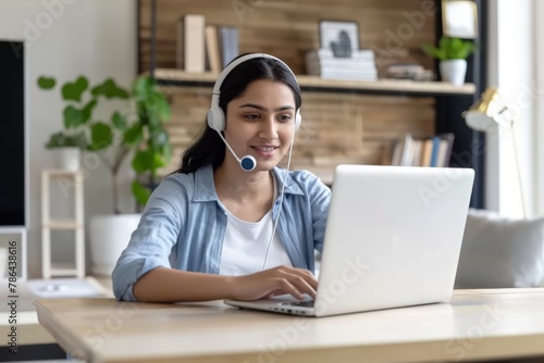 A indian woman using a headset to help a client on a laptop