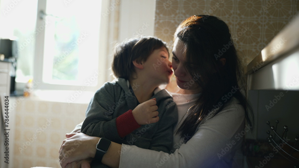 Mother and child bonding relationship at home kitchen. Authentic affectionate moment between son and parent, small boy kissing mom on cheek in genuine laughter and smile Mother and child bonding relationship at home kitchen. Authentic affectionate moment between son and parent, small boy kissing mom on cheek in genuine laughter and smile