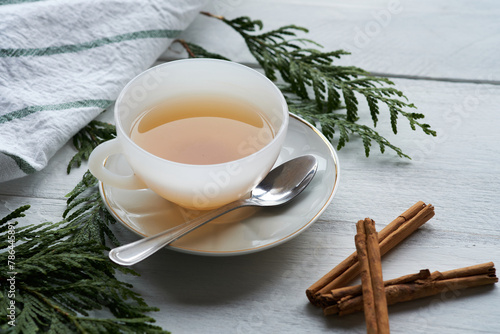 A white ceramic cup with black tea and cinnamon sticks