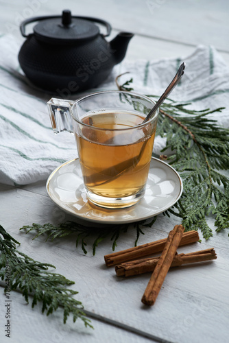 A white ceramic cup with black tea and cinnamon sticks