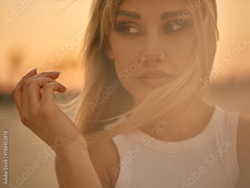 Portrait of a woman with her hair gently blowing in the wind, capturing a sense of mood and movement against a softly blurred background