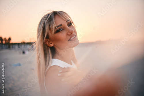 A woman in a serene moment, gazing out to the calm sea during a soothing sunset on a beach