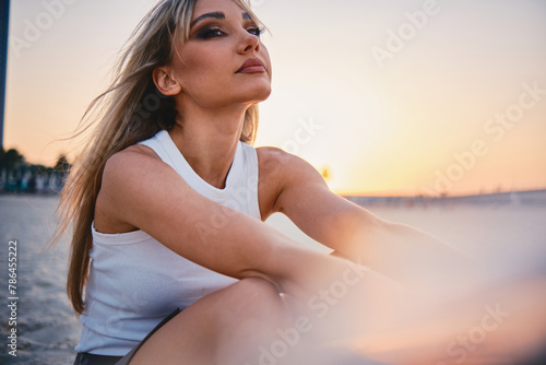 Serene woman in white enjoying a golden sunset, exuding a sense of calm and elegance against an evocative backdrop