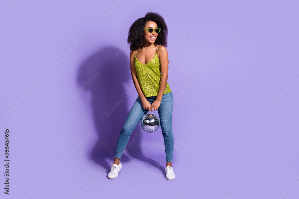 Full length photo of gorgeous young girl sunglass hold discoball wear trendy green sequins outfit isolated on purple color background Full length photo of gorgeous young girl sunglass hold discoball wear trendy green sequins outfit isolated on purple color background