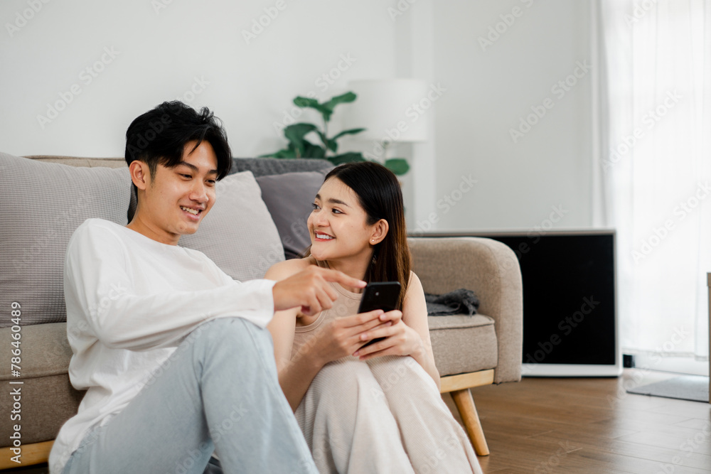 Casual moment captures a couple engaging with content on a smartphone, sharing smiles and a conversation on a comfy couch. Casual moment captures a couple engaging with content on a smartphone, sharing smiles and a conversation on a comfy couch.