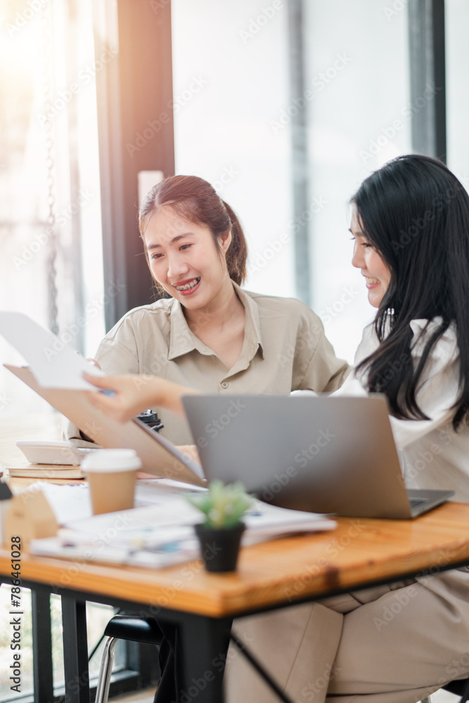 Two female colleagues share a light-hearted moment with coffee during a casual office meeting. Two female colleagues share a light-hearted moment with coffee during a casual office meeting.