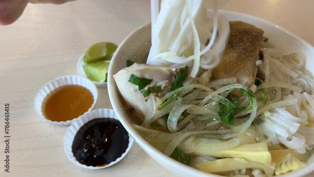 Vietnamese pho with spicy sriracha sauce shot from top to bottom. Woman eat udon Vietnamese pho with spicy sriracha sauce shot from top to bottom. Woman eat udon