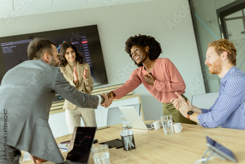 Jubilant business professionals celebrating success with a handshake in a modern office meeting room