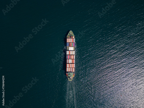 A container ship moves steadily through the ocean, carrying stacked containers