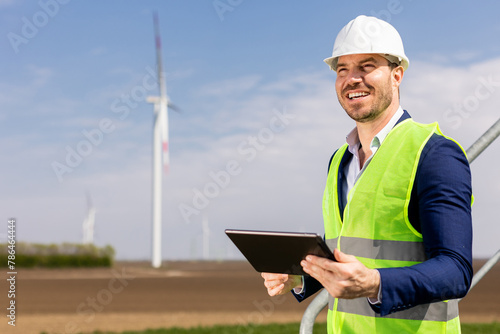 Smiling Engineer With Tablet Inspecting Wind Turbines On A Sunny Day. Generative AI