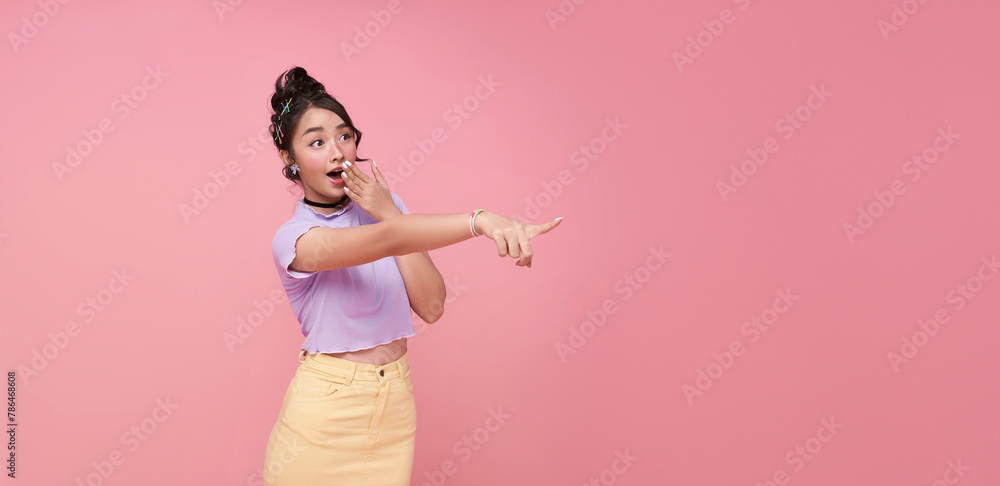 Schilderij op canvas Happy young Asian teen woman standing with her pointing finger isolated on pink background with copy space