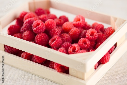 A small wooden crate full of fresh raspberries.