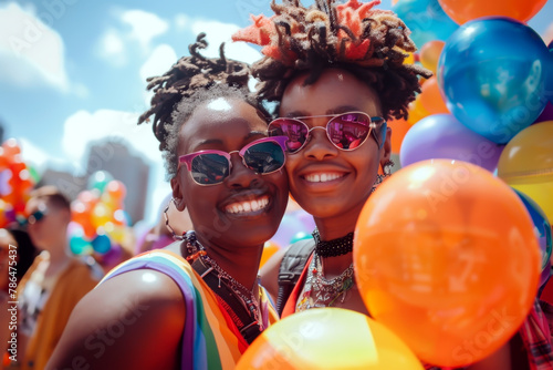 Two joyful African American women celebrating at a Pride parade, surrounded by colorful balloons