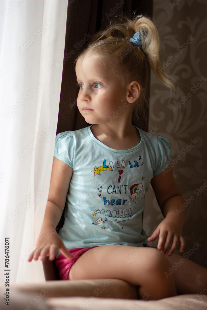 4 year old blonde girl sits by the window and looks out the window
4 year old blonde girl sits by the window and looks out the window