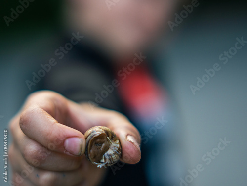 A child hodling a snail. Blurry background.
