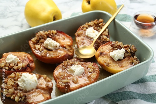 Tasty baked quinces with nuts and cream cheese in dish on table, closeup