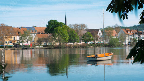 A small boat is on a calm river. During sunset. In a city park in Europe