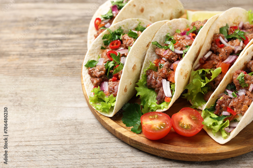 Delicious tacos with meat and vegetables on wooden table, closeup. Space for text Delicious tacos with meat and vegetables on wooden table, closeup. Space for text